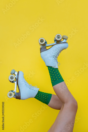 Woman with vintage quad roller skates and green socks on yellow background