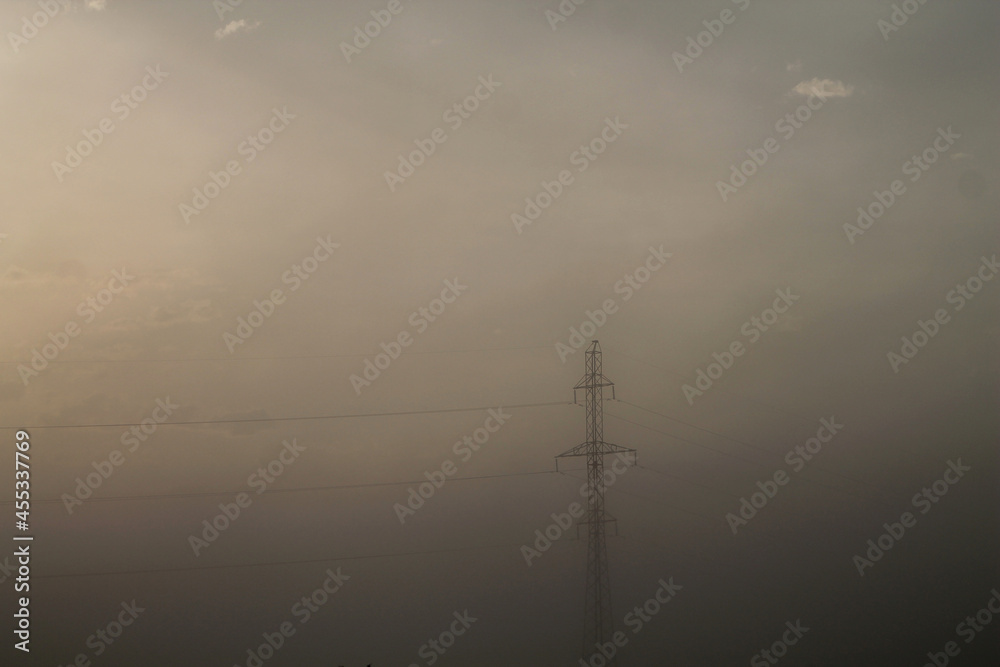 Power lines at sunrise. Power lines at sunrise. Country road at dawn in the fog
Power lines at dawn in the fog. Fog over the field