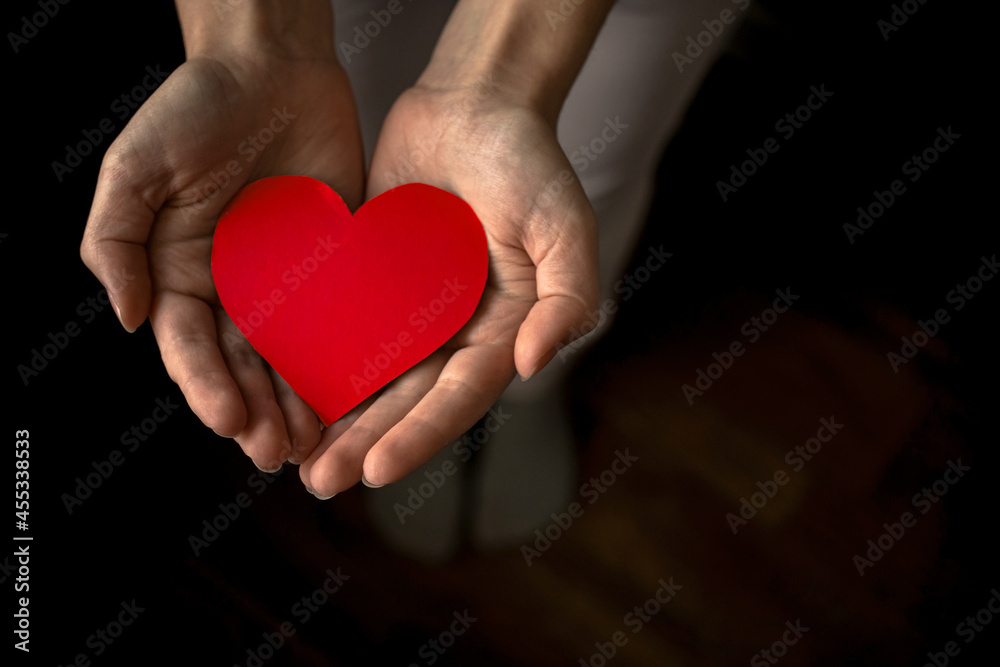 Hands holding red heart on black background. Health insurance, organ donor day, charity concept. World health, mental and heart days concept. All lives matter photo