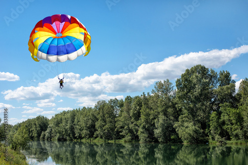 Paragliding over a river and forest on a summer sunny day.