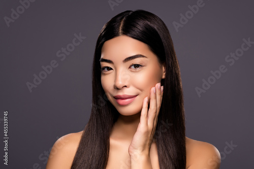 Photo of charming chinese brunette hairstyle lady hand cheekbone enjoy soft facial skin isolated grey color background