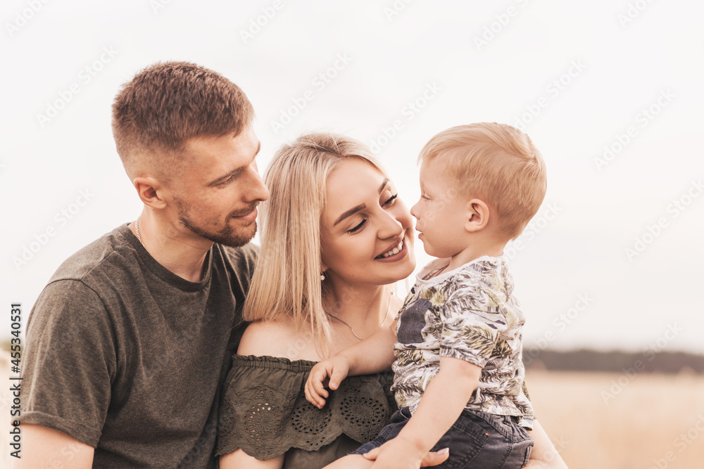 Beautiful family parents and a young son in a wheat field. Mom, Dad and Baby Together. Happy family, parents hugs their little son Beautiful family parents and a young son in a wheat field. Mom, Dad and Baby Together. Happy family, parents hugs their little son