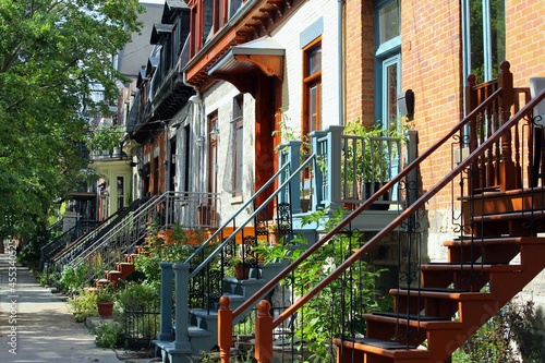 Colored houses with green hydrangea in Montreal, Plateau Mont Royal neighborhood during housing crisis of 2021 with homes and apartment prices reducing mortgage possibilities in gentrification area