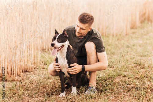 A young man walks in nature with a dog of the Pit Bull Terrier breed