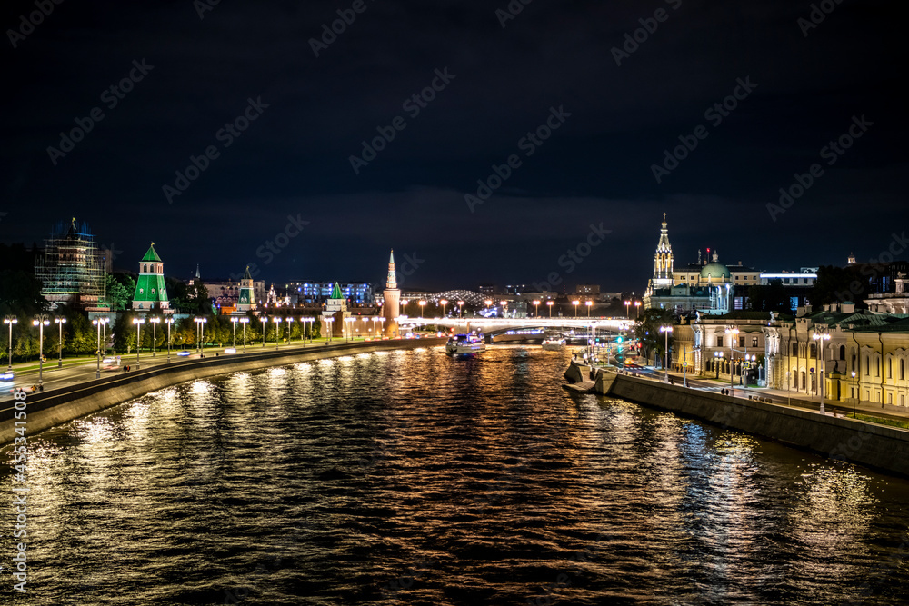 landscape with night river lights reflected in the river and the ancient Kremlin with towers on the bank 