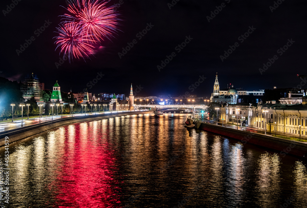 fireworks over the night river with floating motor ships of the embankment and the old Kremlin 