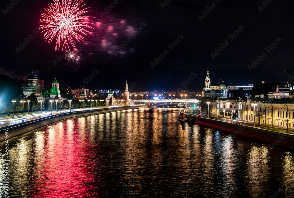 fireworks over the night river with floating motor ships of the embankment and the old Kremlin 