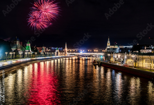 fireworks over the night river with floating motor ships of the embankment and the old Kremlin 