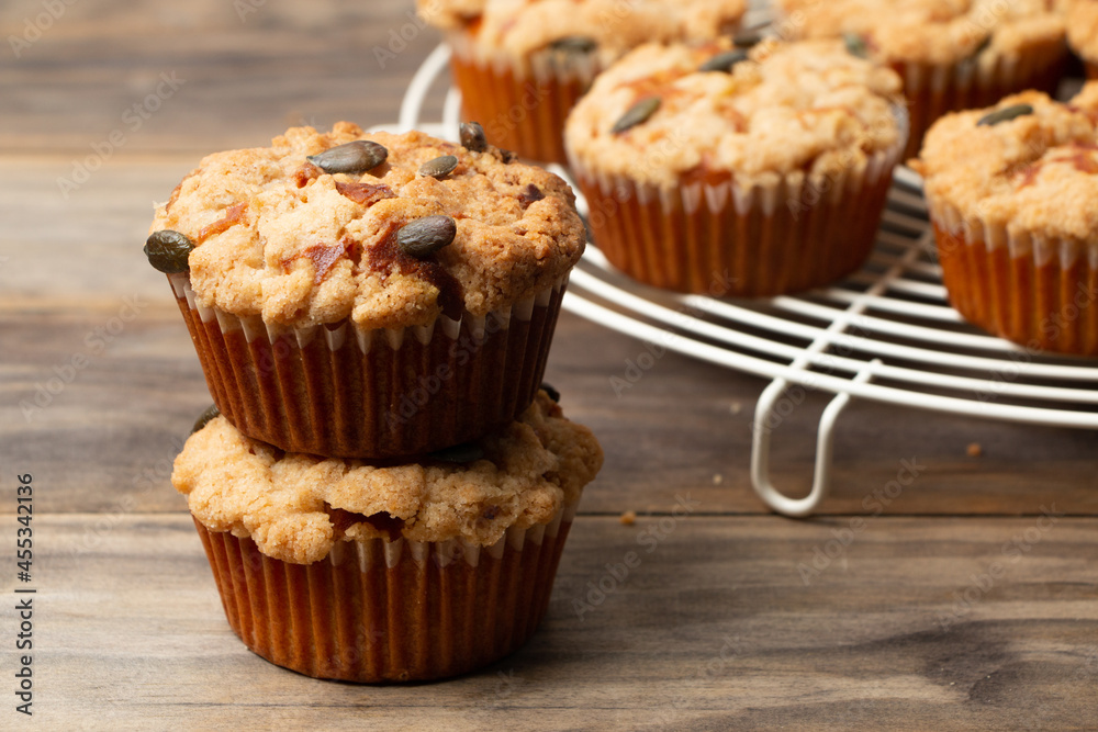 Pumpkin muffins with crumble and seeds on a rustic wooden table Pumpkin muffins with crumble and seeds on a rustic wooden table