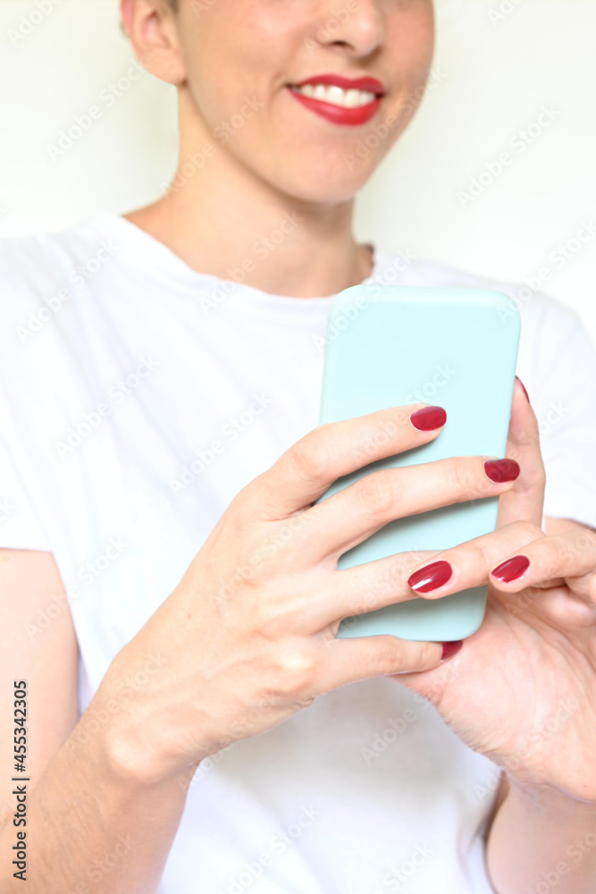 Unrecognizable smiling latina woman with red lips looks at her smartphone Unrecognizable smiling latina woman with red lips looks at her smartphone