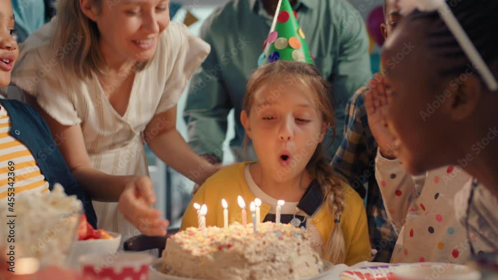 cute birthday girl blowing candles on cake making wish celebrating party with friends children having fun celebration at home 4k footage