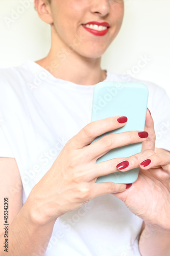 Unrecognizable smiling latina woman with red lips looks at her smartphone