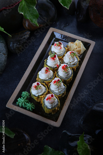 Rolls in tempura with mussels. Traditional Japanese cuisine. Raspberry tobik caviar. Ebi tempura. White ginger. Cocktail shrimp. Vertical photo on black background.Top view. photo