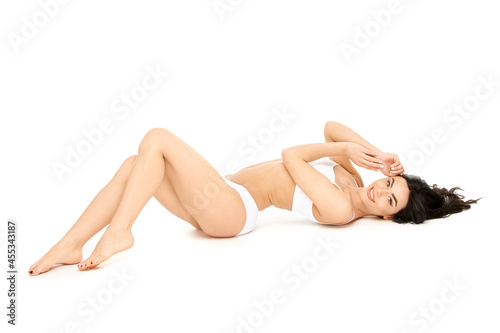 Fitness young woman with a beautiful body sitting on white background