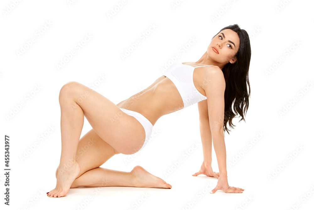 Fitness young woman with a beautiful body sitting on white background