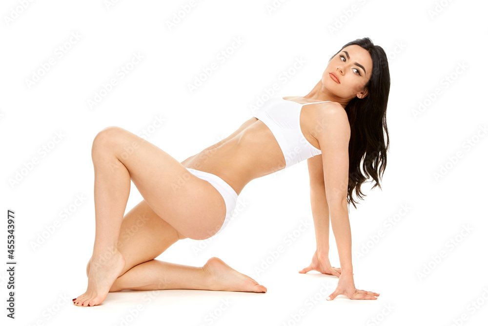 Fitness young woman with a beautiful body sitting on white background Fitness young woman with a beautiful body sitting on white background