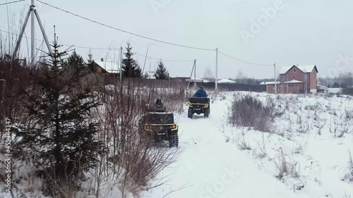 Men ride ATVs on a snowy road photo