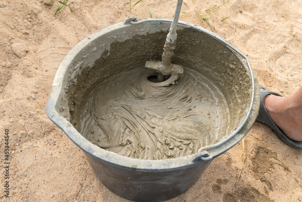 Mixing cement mortar in a bucket with an electric construction drill close-up Mixing cement mortar in a bucket with an electric construction drill close-up