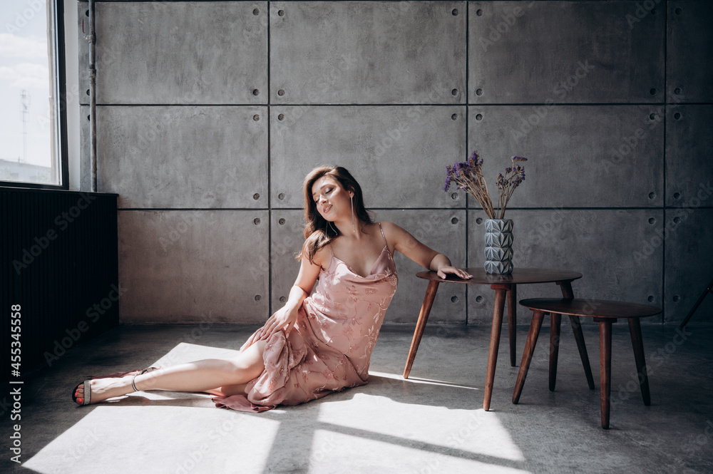 Fototapeta premium a beautiful girl with long hair in a pink dress advertises clothes and smiles