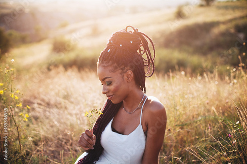 Beautiful black young woman in the park portrait long braids smiling flower