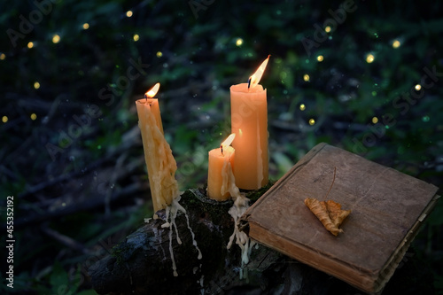 Fotografija magic burning candles and old book in fabulous Night natural Background