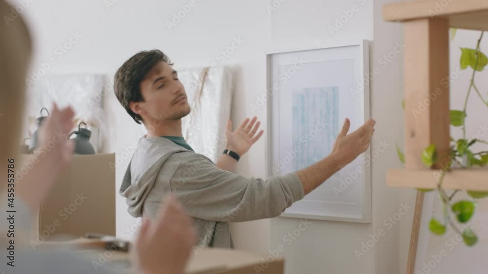 young couple moving into new house hanging picture on wall decorating home together enjoying teamwork in new apartment 4k footage young couple moving into new house hanging picture on wall decorating home together enjoying teamwork in new apartment 4k footage