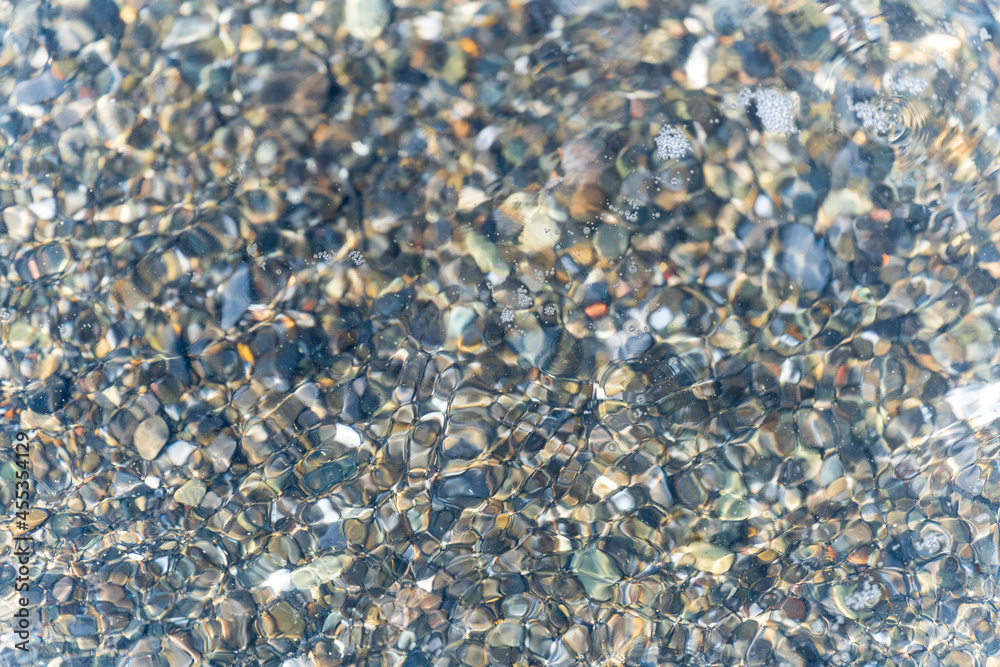 Background of wet pebbles washed by a sea wave
