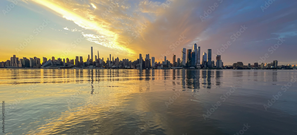 New York, NY - USA - Sept. 4, 2021: Panoramic view of the skyline of the westside of Manhattan at sunrise, with reflections seen in the Hudson River.