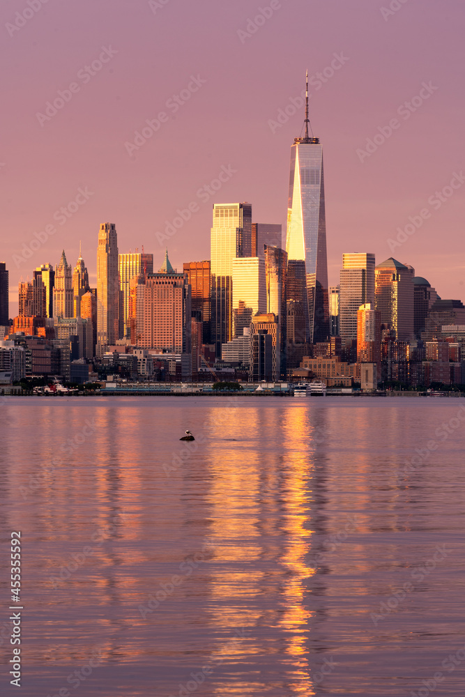 New York, NY - USA - Vertical image of the skyline of Lower Manhattan at sunrise, with reflections seen in the Hudson River. Highlighting the World Trade  Center.