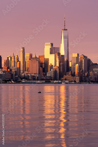 New York, NY - USA - Vertical image of the skyline of Lower Manhattan at sunrise, with reflections seen in the Hudson River. Highlighting the World Trade Center.