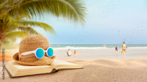 Hat and old books placed on the beach. Beach activities. Vacation in summer.