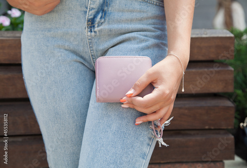 Woman standing on the street holding wallet.
