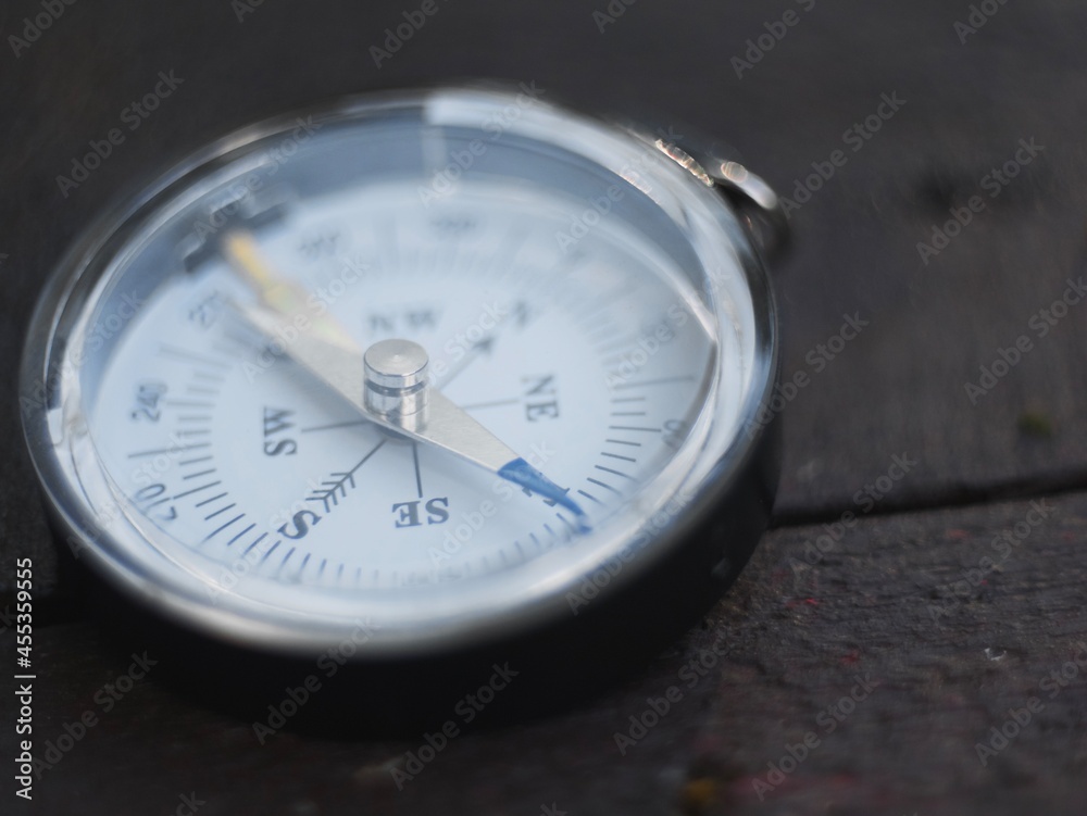 the magnetic compass lies on a wooden surface. the compass indicates the direction the magnetic compass lies on a wooden surface. the compass indicates the direction