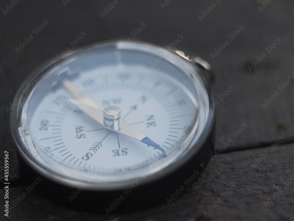 the magnetic compass lies on a wooden surface. the compass indicates the direction the magnetic compass lies on a wooden surface. the compass indicates the direction