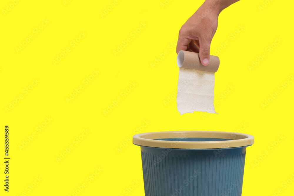 Used and finished roll of toilet paper is thrown into trash on yellow background. Used and finished roll of toilet paper is thrown into trash on yellow background.