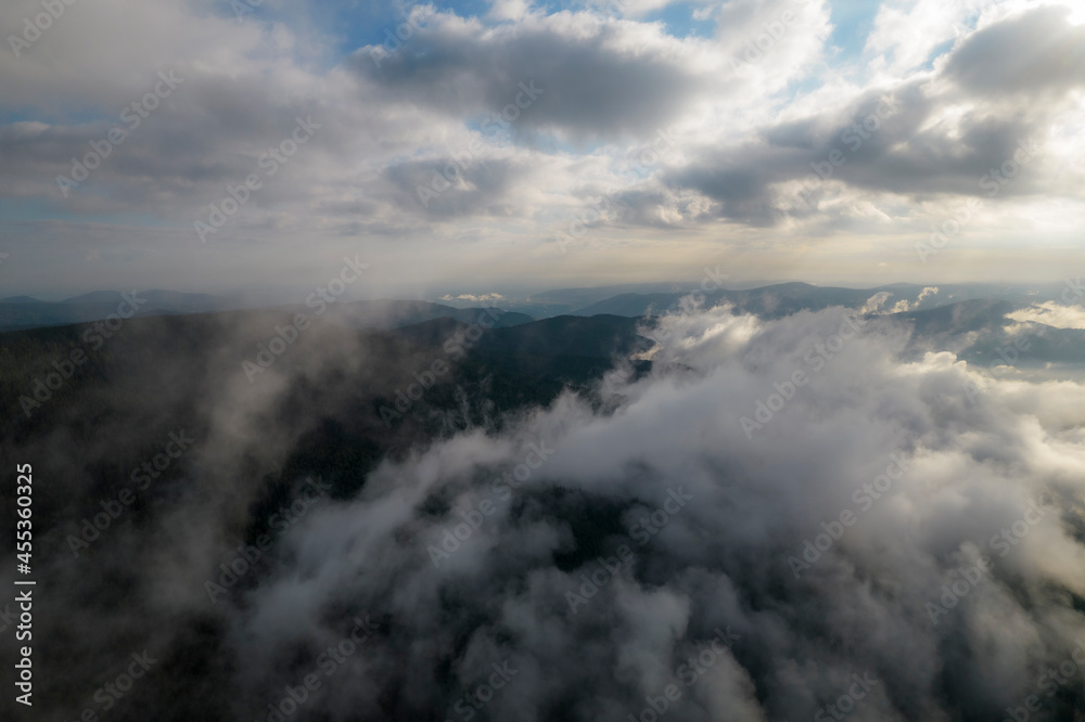 Foggy weather in mountains. Misty fog blowing over pine tree forest. Aerial view of spruce forest trees on the mountain hills at misty day. Morning fog at beautiful summer forest. Foggy weather in mountains. Misty fog blowing over pine tree forest. Aerial view of spruce forest trees on the mountain hills at misty day. Morning fog at beautiful summer forest.