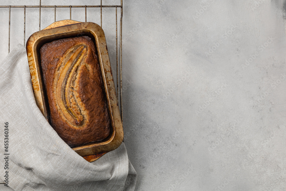 Fresh banana bread in a baking dish on a wire rack in the oven on a light background