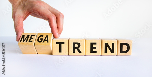 Trend or megatrend symbol. Businessman turns wooden cubes and changes words trend to megatrend. Beautiful white table, white background, copy space. Business, trend or megatrend concept. photo