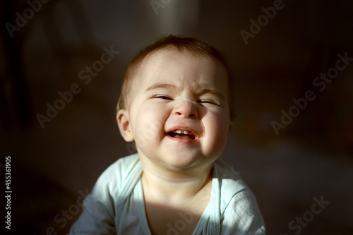 Close-up portrait of a baby smiling on a dark background.