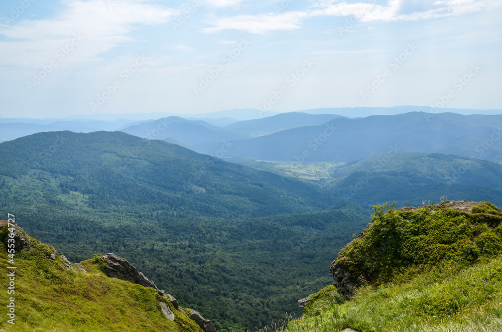 Carpathians mountain hills, covered rocks and grassy slope with forest and mountain range. beautiful summer landscape. Ukraine
