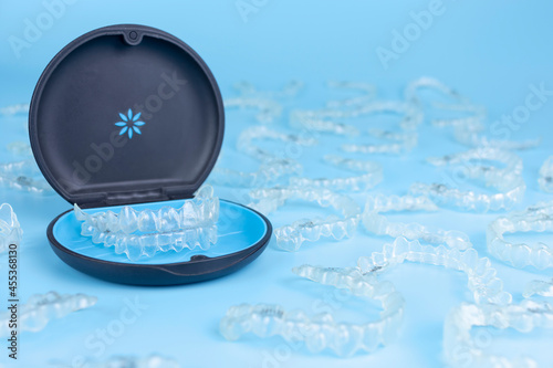 Invisible retainers case with orthodontic aligner brackets. Black plastic dental container for removable invisalign braces on blue background