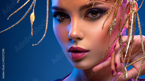 Stylish fashion model with a golden decoration around her face. Beauty style. Art portrait of a beautiful woman with bright makeup. Closeup model face with vivid eye make-up.