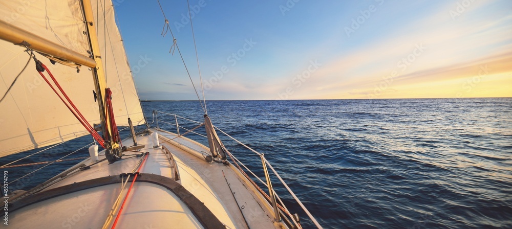 Yacht sailing in an open sea at sunset. Close-up view of the deck, mast ...