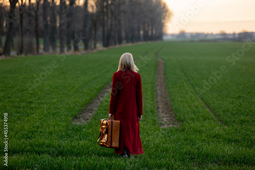 Style blonde woman with suitcase at countryside