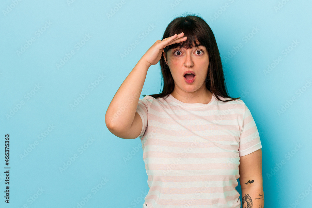 Young curvy caucasian woman isolated on blue background shouts loud, keeps eyes opened and hands tense. Young curvy caucasian woman isolated on blue background shouts loud, keeps eyes opened and hands tense.