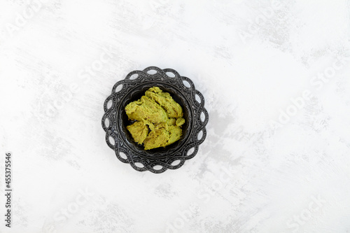 Turkish Halva with pistachio flavor in metal plate with an ornament. Oriental sweets. Light background, Selective focus, copy space