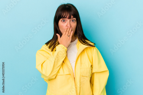 Young curvy caucasian woman isolated on blue background shocked, covering mouth with hands, anxious to discover something new.