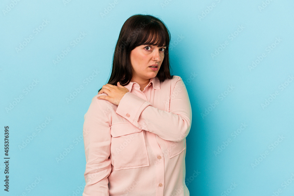 Fototapeta premium Young curvy caucasian woman isolated on blue background having a shoulder pain.