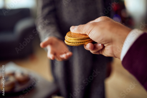 фотографія Close-up of father gives Hanukkah gelt to his daughter during Jewish festival of lights at home