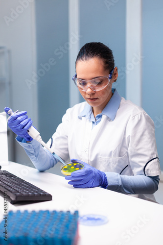 Scientist researcher putting medical solution using micropippete in petri dish with bacteria working at microorganism experiment in microbiology hospital laboratory. Doctor examining vaccine infection photo